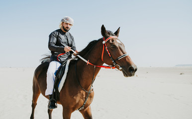 Obraz premium Arabian man with traditional clothes riding his horse