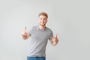 Man pointing at his t-shirt against light background