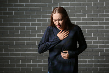 Woman having panic attack against brick wall