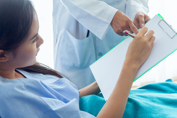 The patient, an Asian woman, is testing the writing of letters. With the right hand On white paper To test the hand senses As doctor ordered to check treatment results. In the patient&rsquo;s ward.