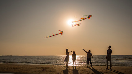 Friendly family plays with kites on the seashore.