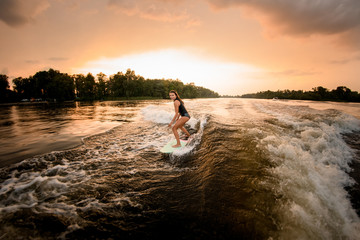 Girl riding on the wakeboard on the river on the wave of the motorboat