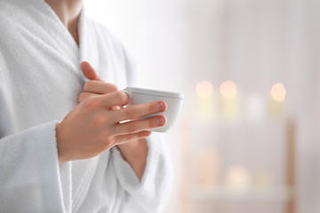 Young man in bathrobe drinking coffee at home, closeup