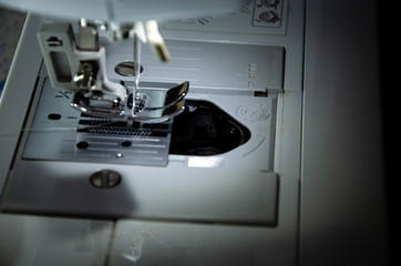 sewing machine foot while working with female hands close