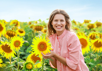 Beautiful young woman in sunflower field on summer day