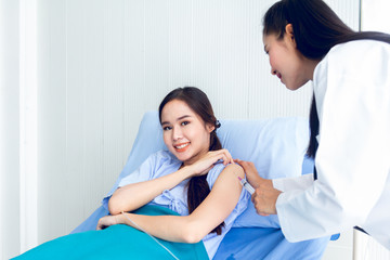 Asian young female doctor being injecting a young woman patient, who shows anxious facial expression and lying in bed In the room to treat the illness better.