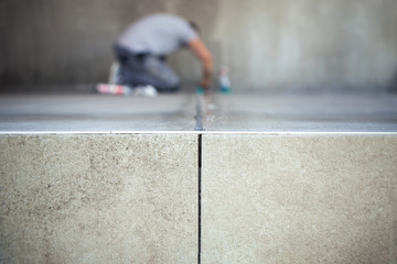 Construction worker filling the gap between the just glued ceramic tiles.
