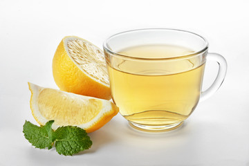 Glass cup of tasty tea with mint and lemon on white background