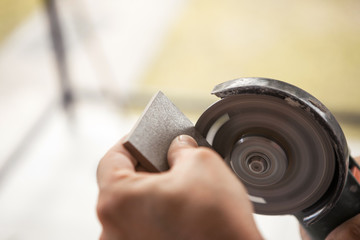 A construction worker cuts a ceramic tile with a grinder