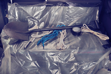 Car trunk of killer's vehicle prepared with plastic foil, ropes, tapes and weapons