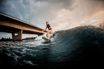 Girl riding on the wakeboard on the river in the background of the bridge