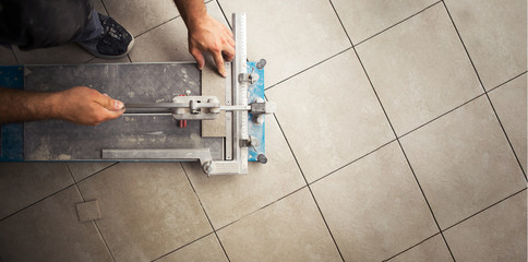 Top view of a construction worker cutting a tile using a tile cutting machine.