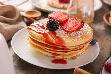 Plate with tasty pancakes on wooden table