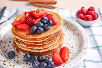 Plate with tasty pancakes and berries on table