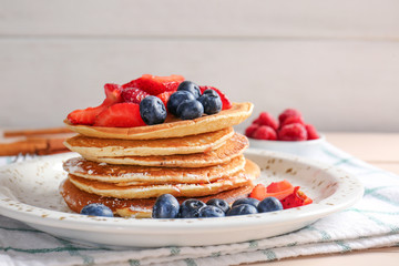 Plate with tasty pancakes and berries on table
