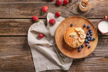 Plate with tasty pancakes on wooden table