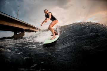 Smiling girl riding on the wakeboard on the river in the background of the huge bridge