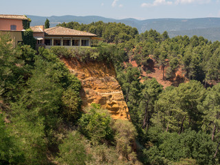 Fototapeta na wymiar ROUSSILLON, France, august 2019: A view of the red ochre cliffs of Roussillon, ranked as one of the most beautiful villages of France