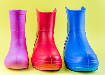 red blue and pink rubber boots EVA on a yellow background