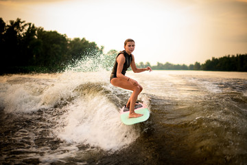 Woman riding on the wakeboard on the river in the background of trees
