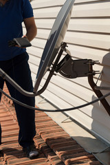 the worker repair the antenna at the house roof with satellite device.