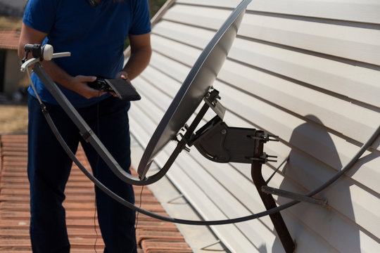 the worker repair the antenna at the house roof with satellite device.