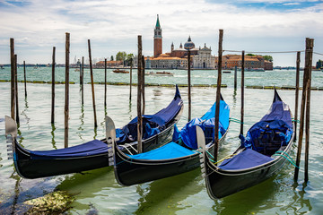 Fototapeta na wymiar Traditional gondolas floating on the canal in Venice, in front of island San Giorgio Maggiore, Italy
