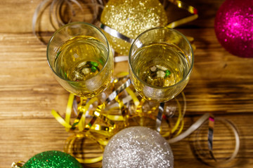 Two glasses of champagne and festive Christmas decorations on wooden table. Top view. Christmas and New Year celebration