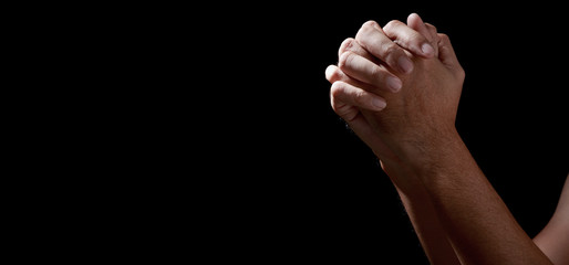 Fototapeta premium Man hands in praying position low key image. High Contrast isolated on Black Background. COPY SPACE.