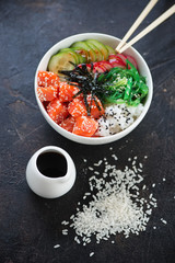 Poke bowl with salmon over dark brown stone background, vertical shot