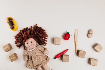A doll, toy food and wooden squares on a white background
