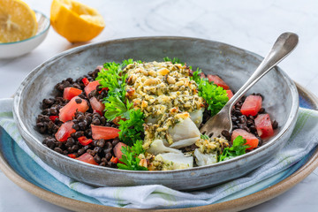 Pesto-crusted cod with Puy lentils and tomatoes in a bowl