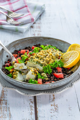 Pesto-crusted cod with Puy lentils and tomatoes in a bowl