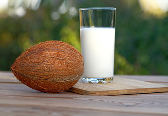 Coconut milk on a wooden table against the background of the garden.