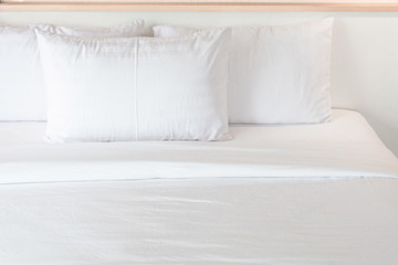 Three white pillows neatly arranged on the white bed. Hotel service.