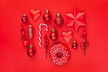 Red Christmas composition with red holly berries, Xmas candy, baubles and star on colorful red background. Xmas flat lay top view with New Year decoration