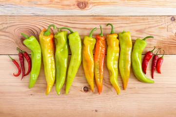 A pile of pepper on a wooden table. Hot green, orange pepper. Rustic style. Food background. Top view.