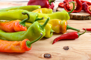 A pile of pepper on a wooden table. Hot green, orange pepper. Rustic style.