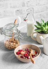 Delicious healthy breakfast - granola with fresh berries and coconut milk on a light background. Flat lay