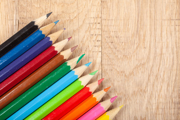 Close up of multicolored pencils on wooden background