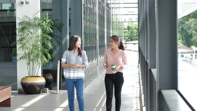 Urban city lifestyle. Two Asian woman walking and talking on downtown street.