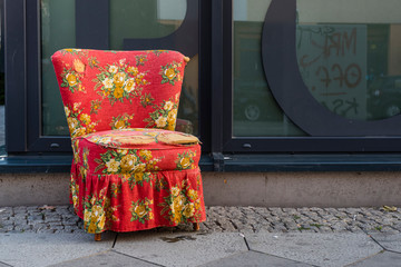 An red armchair on the sidewalk, bulky waste on sidewalk, vintage armchair on sidewalk