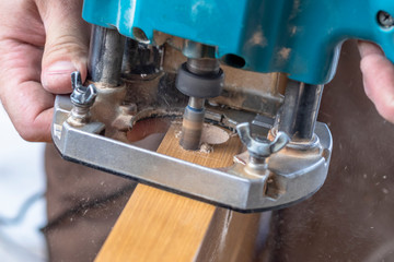Installing a door, Install a door lock, use a milling saw, a carpenter close-up holds a green electric drill