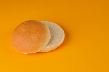 Burger bun empty isolated. American food classic round burger bread isolated on a orange background. Grilled burger bun top.