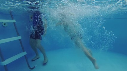 coach teaches the child to swim in the pool.