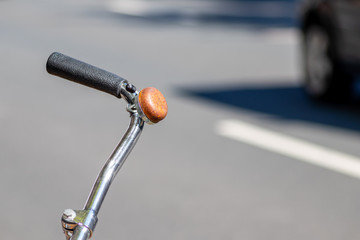 Rostige Fahrradklingel am verchromten Lenker eines Fahrrads vor einer Straße mit Autos im...