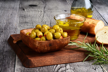 wood bowl of pimento olives with bread and oil