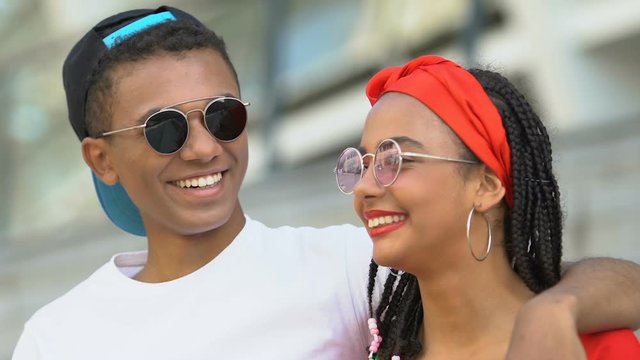 Happy Afro-American teen couple laughing, enjoying show at stadium, leisure time