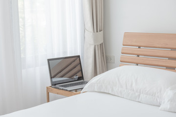 Computer notebook in modern white bedroom interior in morning light
