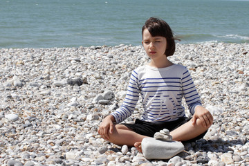 Fototapeta na wymiar calm child meditating for inner peace, wellbeing and wisdom, beach